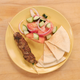 Plate with meat skewer, salad, and pita triangles
